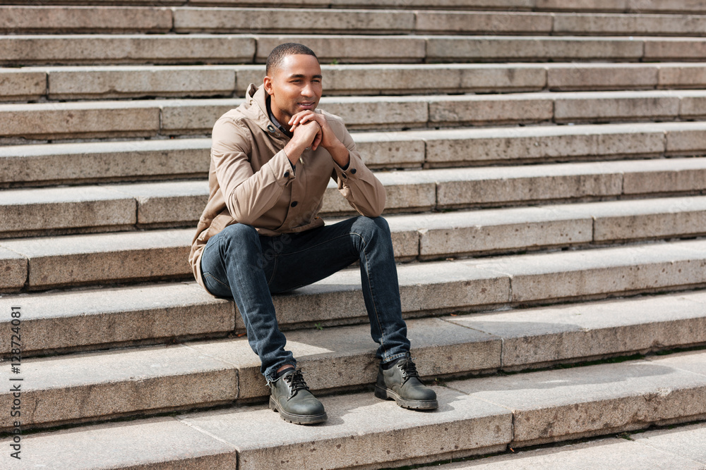 Cheerful young african man sitting on staircase