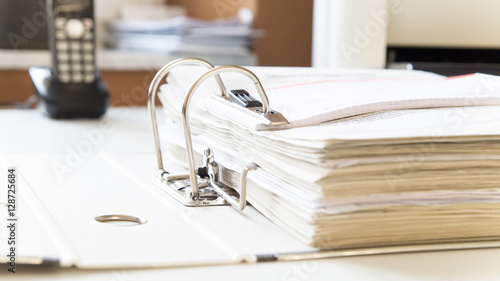 Aktenordner mit Steuerunterlagen für Finanzamt auf Schreibtisch mit Telefon und Drucker im Hintergrund