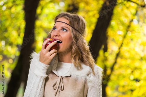 Beautiful boho girl enjoys eating apple in the park.    