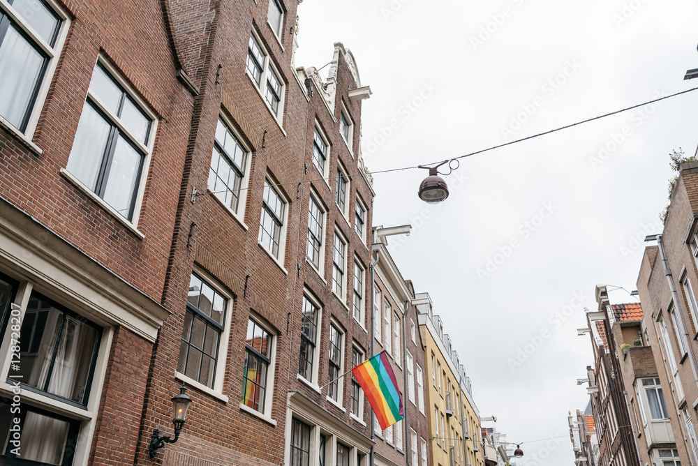 Gay Pride flag in a building in Amsterdam, low angle view against cloudy sky