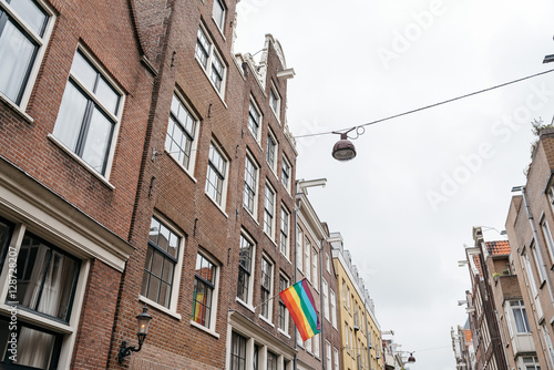 Gay Pride flag in a building in Amsterdam, low angle view against cloudy sky © jjfarq