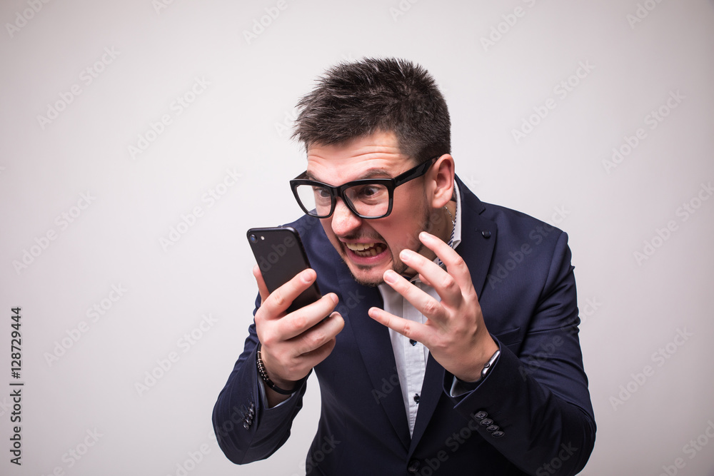 Irritated man in suit with phone isolated white background Irritated man in suit with phone isolated white background