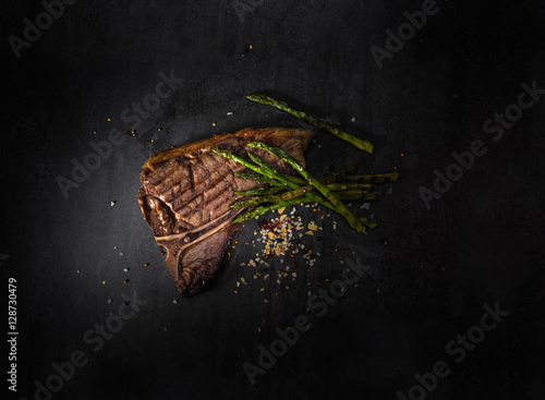 t bone steak with asparagus on black slate