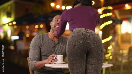 Attractive young woman flirting with boyfriend as he sits at coffee shop