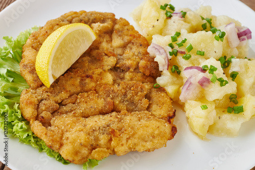 Weiner schnitzel with potato salad on a wooden background
