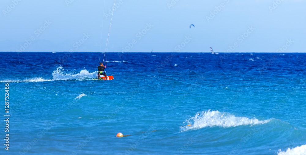 kite surfer rides on the waves of Aegean Rhodes Greece.  bright Sunny day