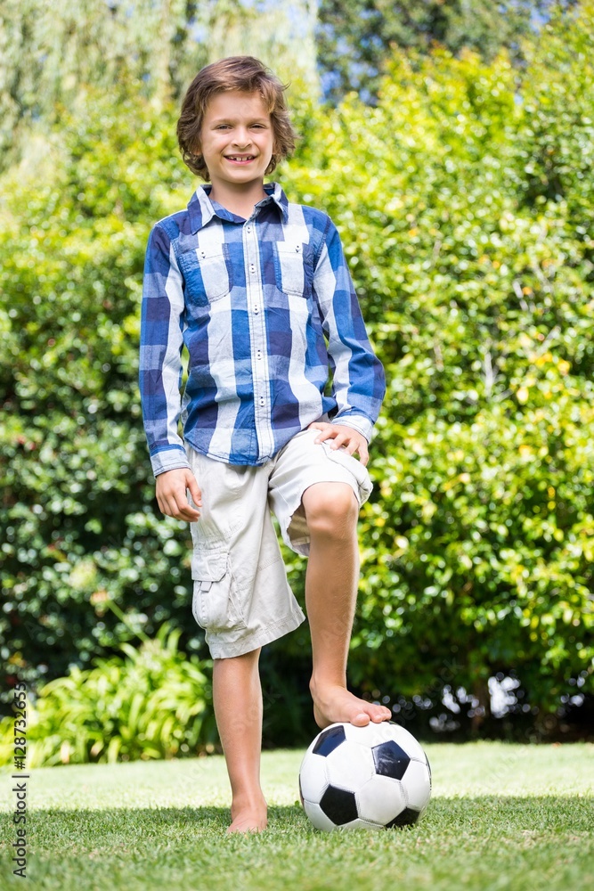 Cute boy smiling and posing with his foot on a soccer ball