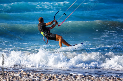 Kitesurfing. Kitesurfer rides the waves on high speed at sunset