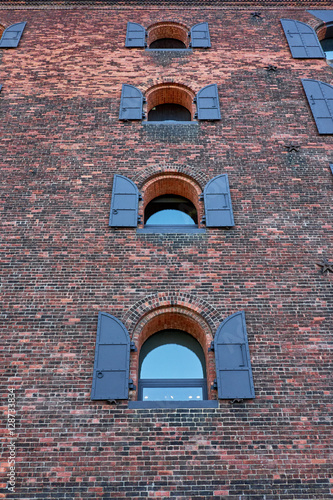 Several arched windows with shutters, fastened to a brick facade of a former industrial building in Dumbo New York photo