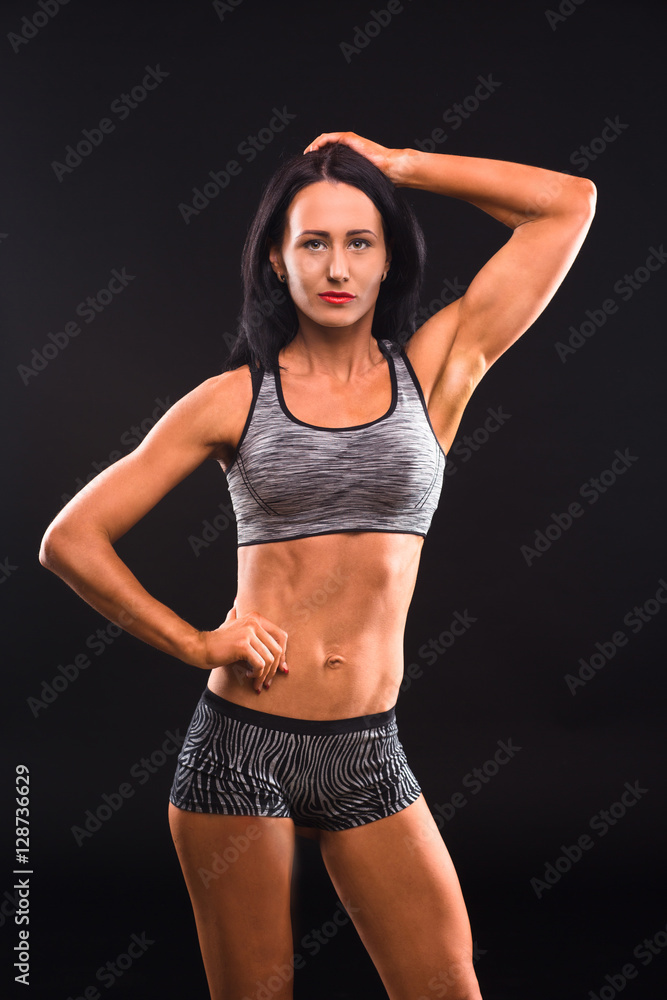 Fitness concept. Picture of beautiful brunette fitness or sports lady looking at camera while demonstrating her perfect abs and body in general. Fitness concept. Picture of beautiful brunette fitness or sports lady looking at camera while demonstrating her perfect abs and body in general.