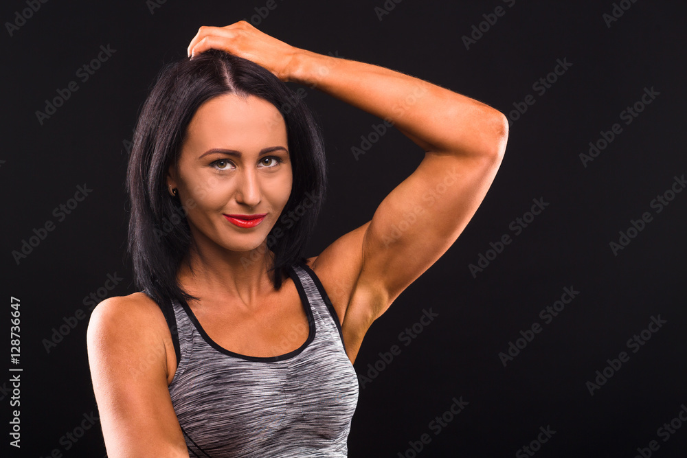 Closeup portrait of beautiful brunette fitness or sports lady smiling for camera while posing isolated on black background in studio. Closeup portrait of beautiful brunette fitness or sports lady smiling for camera while posing isolated on black background in studio.