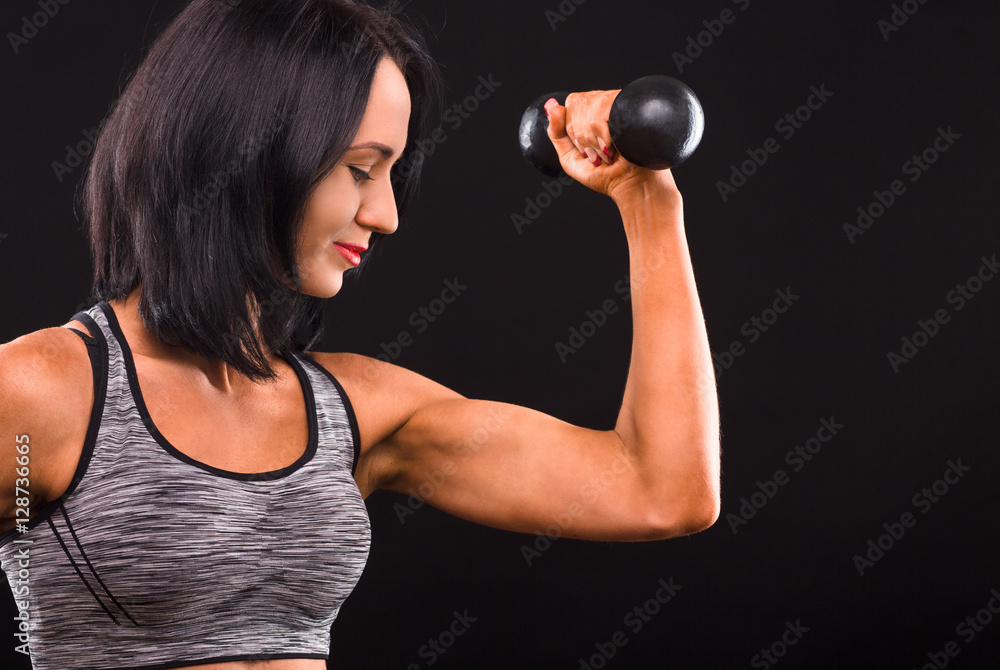 Sports and bodybuilding concepts. Profile of fitness woman training with dumbbells. Beautiful lady demonstrating her perfect biceps in studio. Sports and bodybuilding concepts. Profile of fitness woman training with dumbbells. Beautiful lady demonstrating her perfect biceps in studio.