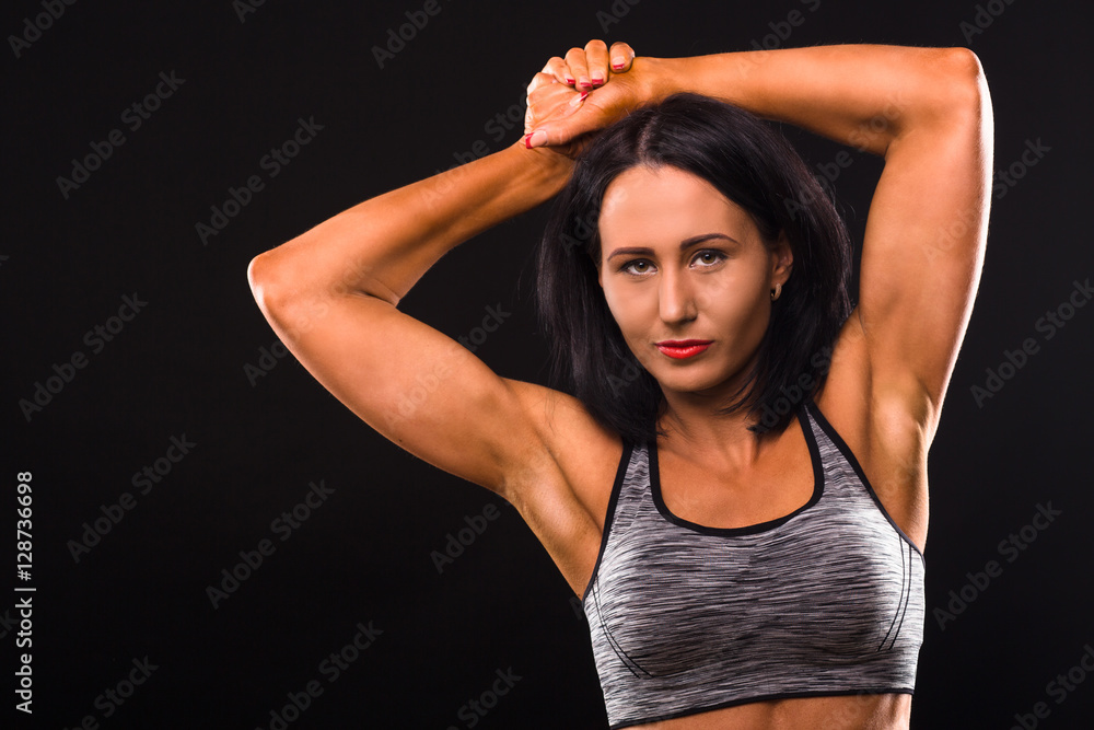 Sports concept. Fitness lady with red lips posing for photographer in studio. Sports lady showing her biceps and smiling for camera. Sports concept. Fitness lady with red lips posing for photographer in studio. Sports lady showing her biceps and smiling for camera.