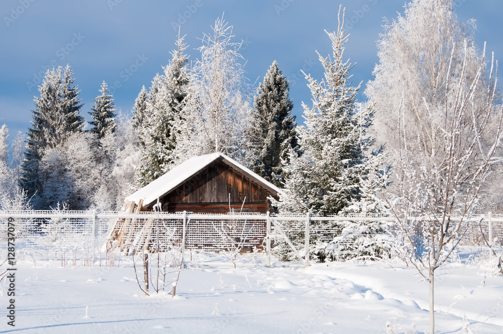 Winter country landscape with wooden house behind a fence in the forest Winter country landscape with wooden house behind a fence in the forest