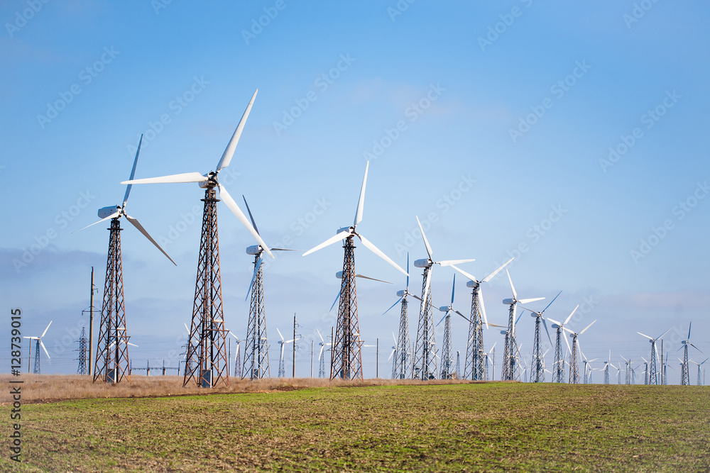 View of many wind turbines on blue sky background. Concept of green energy View of many wind turbines on blue sky background. Concept of green energy