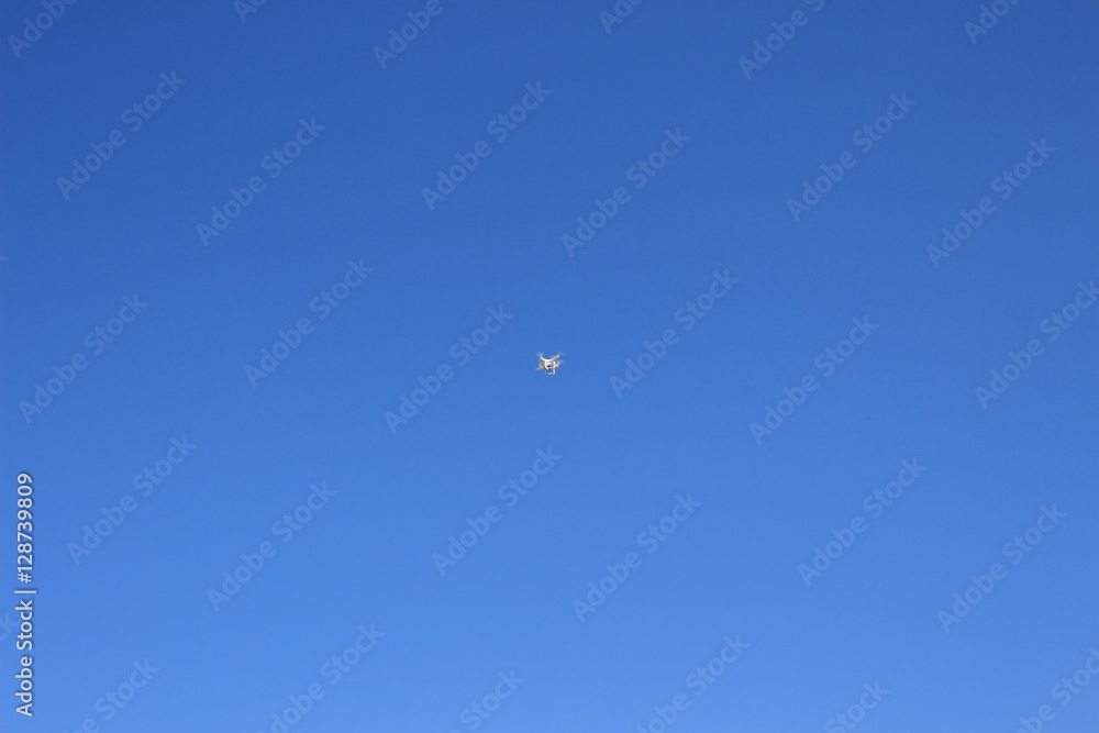 white drone hovering in a bright blue sky white drone hovering in a bright blue sky