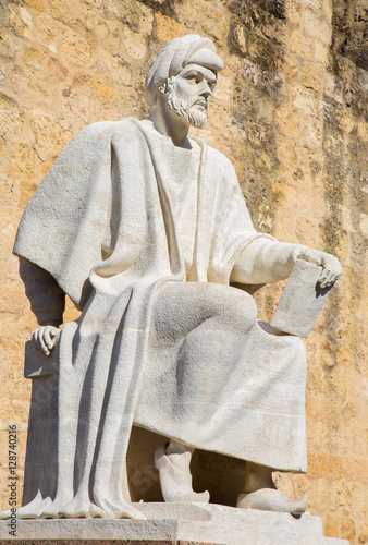 CORDOBA, SPAIN - MAY 25, 2015: The statue of medieval arabic philosopher Averroes by Pablo Yusti Conejo (1967) and the medieval walls. photo