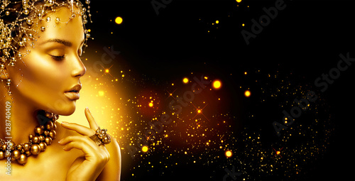 Golden woman. Beauty fashion model girl with golden make up, hair and jewellery on black background © Subbotina Anna