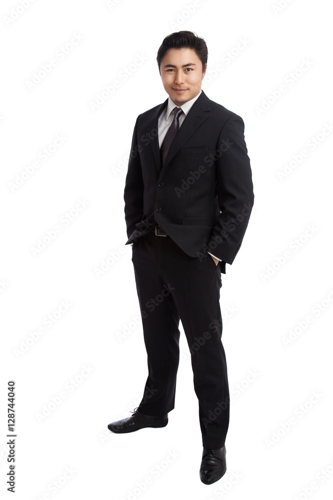 Attractive businessman in a black suit and grey tie, standing against a white background with his hands in pockets. Attractive businessman in a black suit and grey tie, standing against a white background with his hands in pockets.