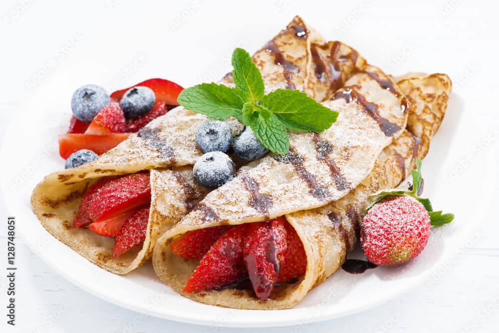 crepes with berries and chocolate sauce on plate