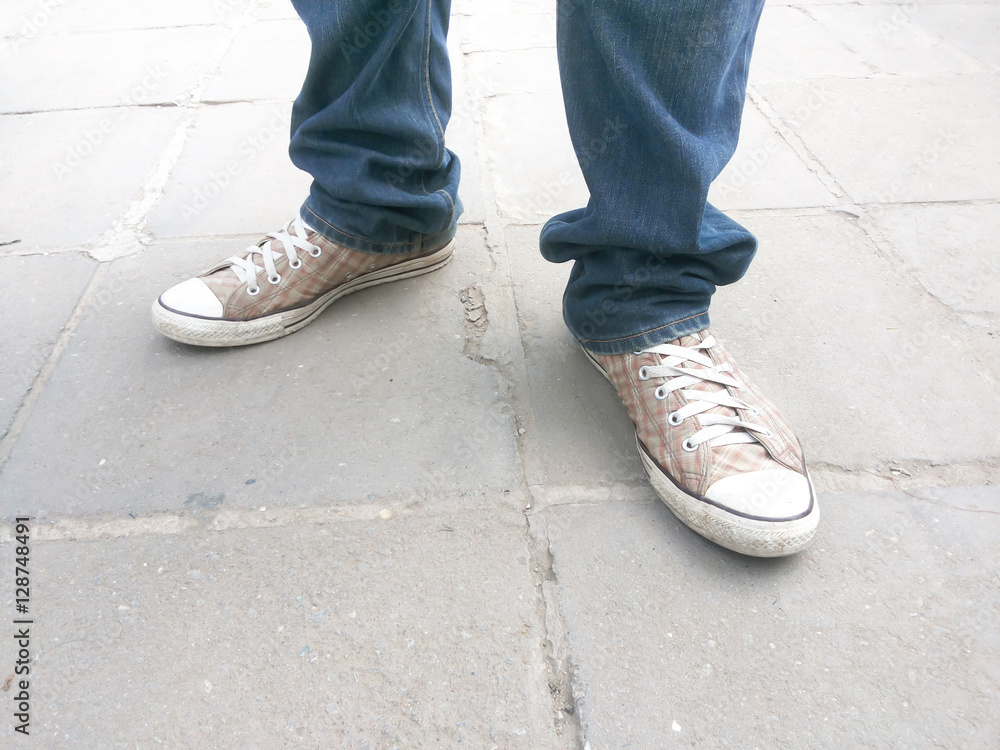 Men's feet in sneakers standing on a concrete background
