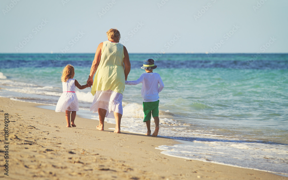 Happy grandmother with kids- little boy and girl- at beach