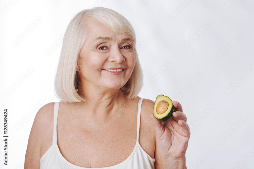 Cheerful nice woman holding an avocado half Cheerful nice woman holding an avocado half