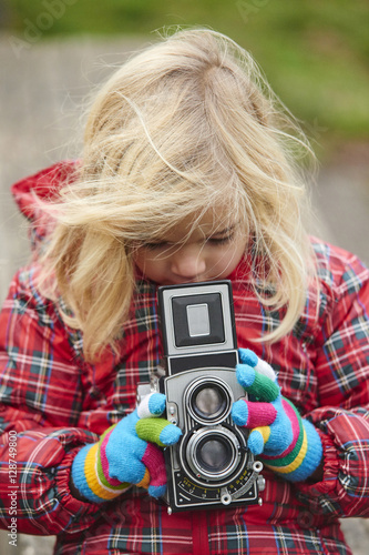 Portrait of little girl child with retro vintage Twin-lens reflex camera outdoors in winter day