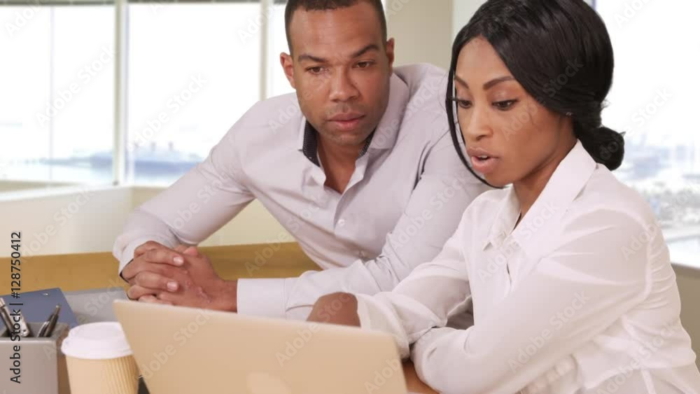 African American Business man and woman looking over figures on laptop African American Business man and woman looking over figures on laptop