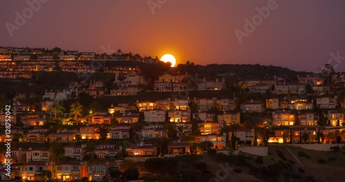 Timelapse of the Full moon rising over many hilltop large Estates homes in Newport Coast / Newport Beach, California. The warm hue on the homes is a result of the setting sun illuminating the homes.