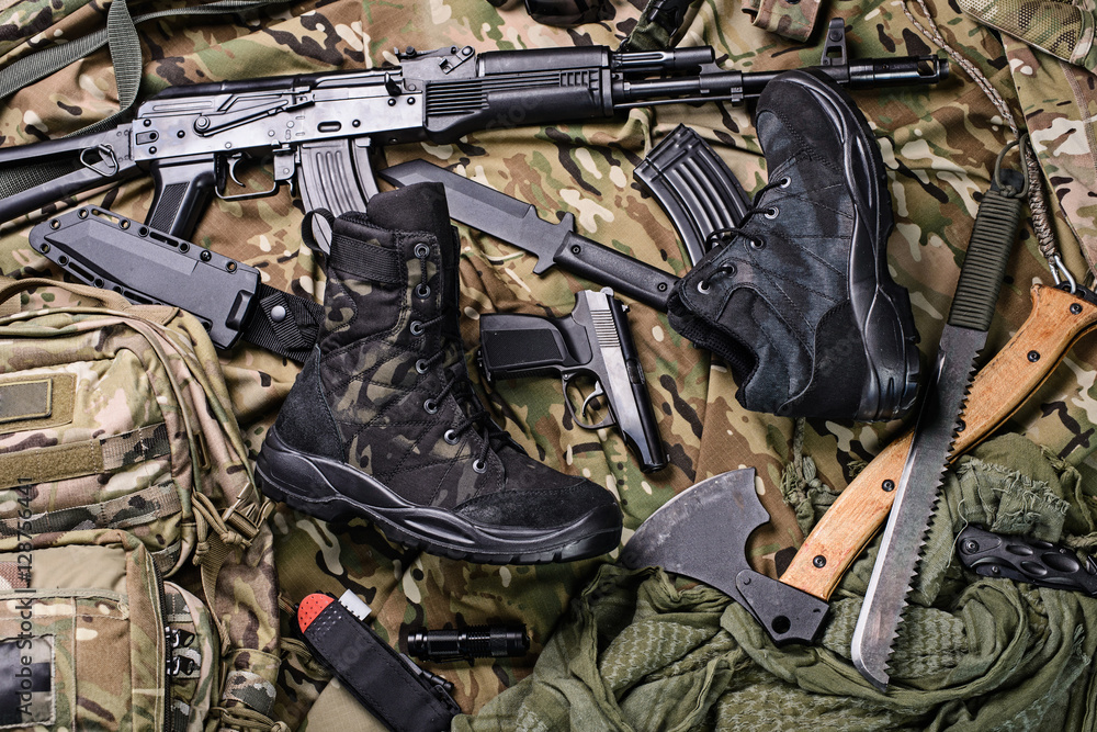 Military clothing-shoes and variety of weapons.Top view/Army boots, ax, gun, machete, knife and rifle top view.Selective focus