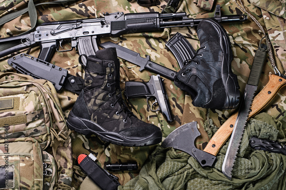 Military clothing-shoes and variety of weapons.Top view/Army boots, ax, gun, machete, knife and rifle top view.Selective focus Military clothing-shoes and variety of weapons.Top view/Army boots, ax, gun, machete, knife and rifle top view.Selective focus
