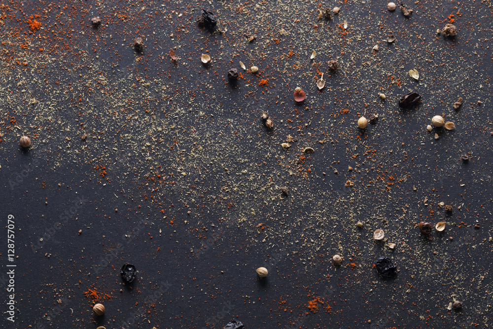 Spicy background with assortment of different hot chili peppers and mix of other spices on a dark background Spicy background with assortment of different hot chili peppers and mix of other spices on a dark background