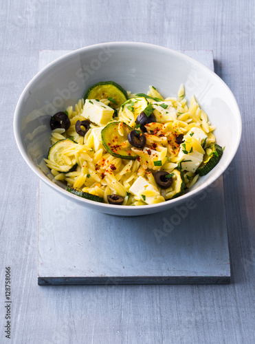 Rice noodles in a bowl with zucchini, feta, and olives photo