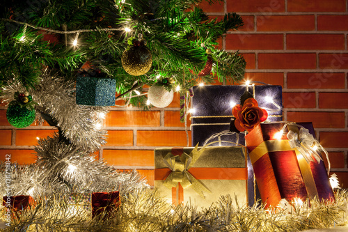 Christmas gift and Christmas tree with light and orange brick wall background. photo