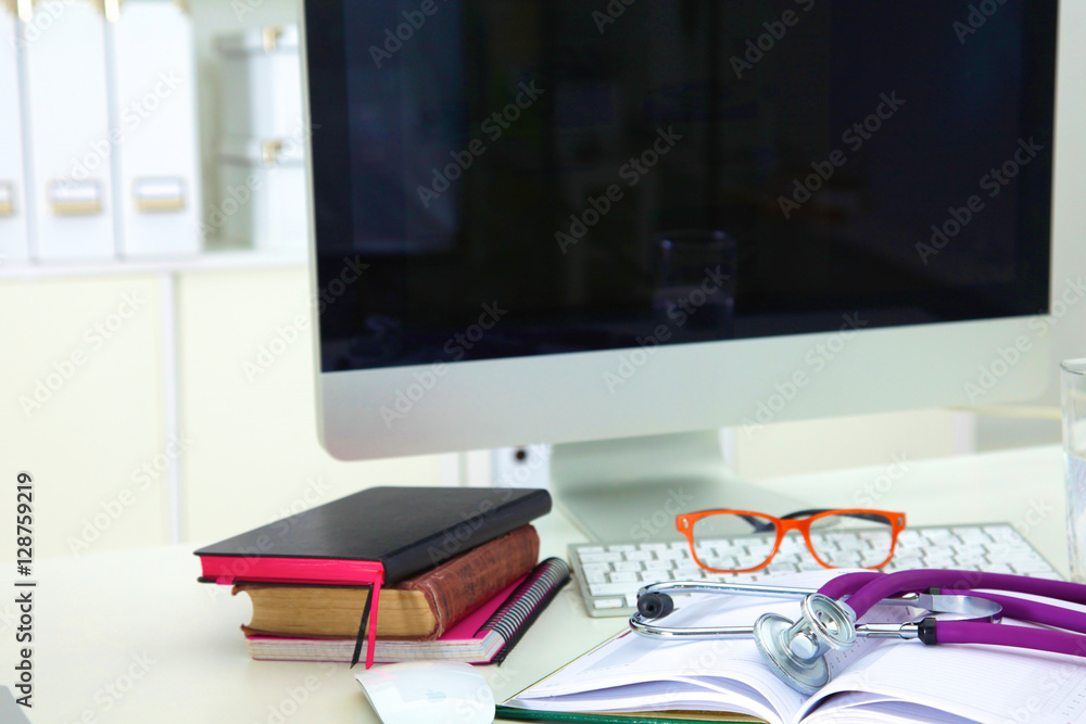 Naklejka premium Medical stethoscope with old books and laptop on a table
