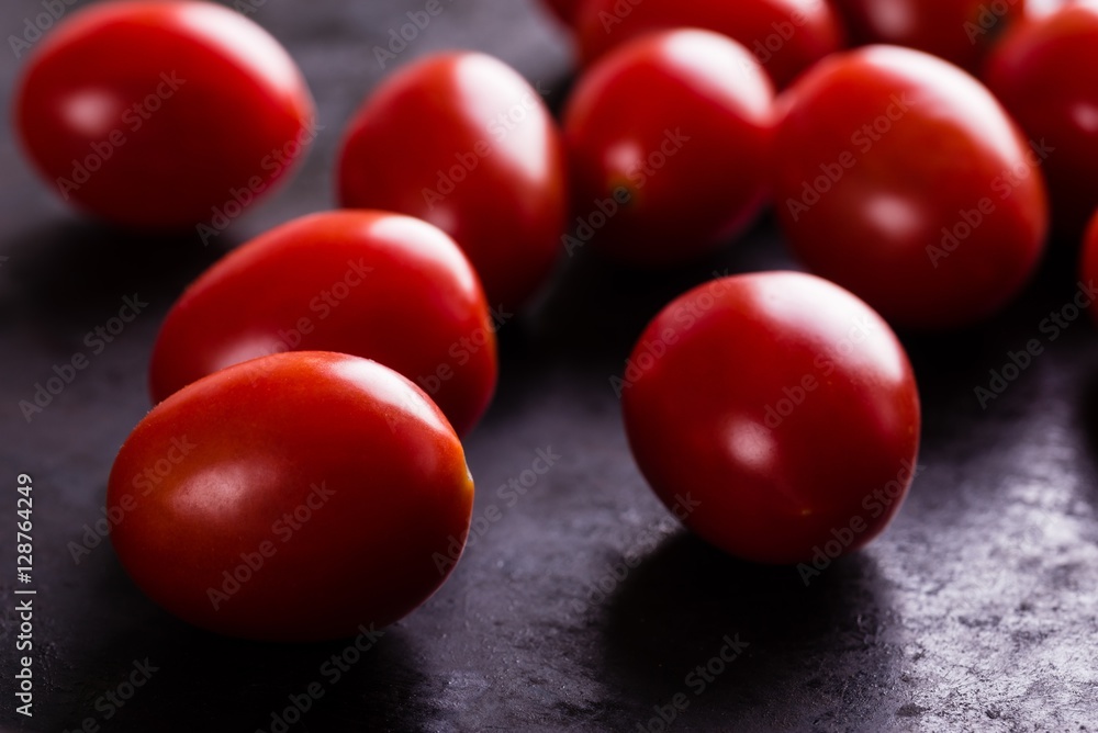 Detail of several red cherry tomatoes on black board Detail of several red cherry tomatoes on black board