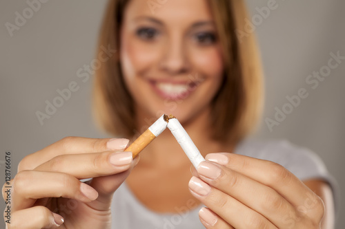 happy young beautiful woman holding a broken cigarette photo
