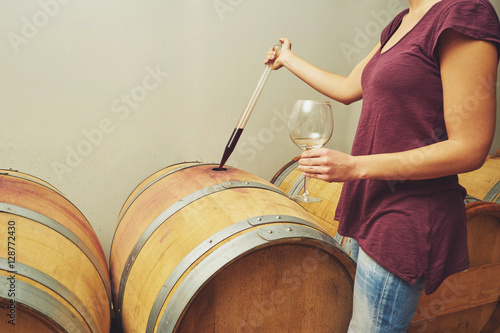 Winemaker getting sample of red wine from barrel. photo