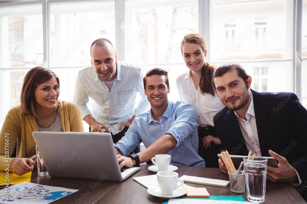 Obraz premium Smiling business people with laptop in meeting room