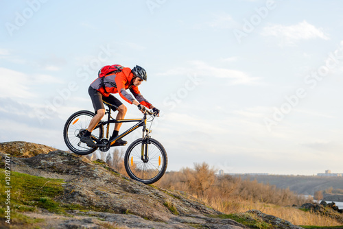 Cyclist in Red Jacket Riding the Bike Down Rocky Hill. Extreme Sport.