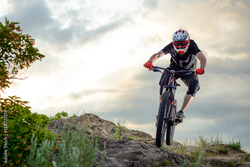 Professional Cyclist Riding the Bike Down Rocky Hill at Sunset. Extreme Sport. Professional Cyclist Riding the Bike Down Rocky Hill at Sunset. Extreme Sport.