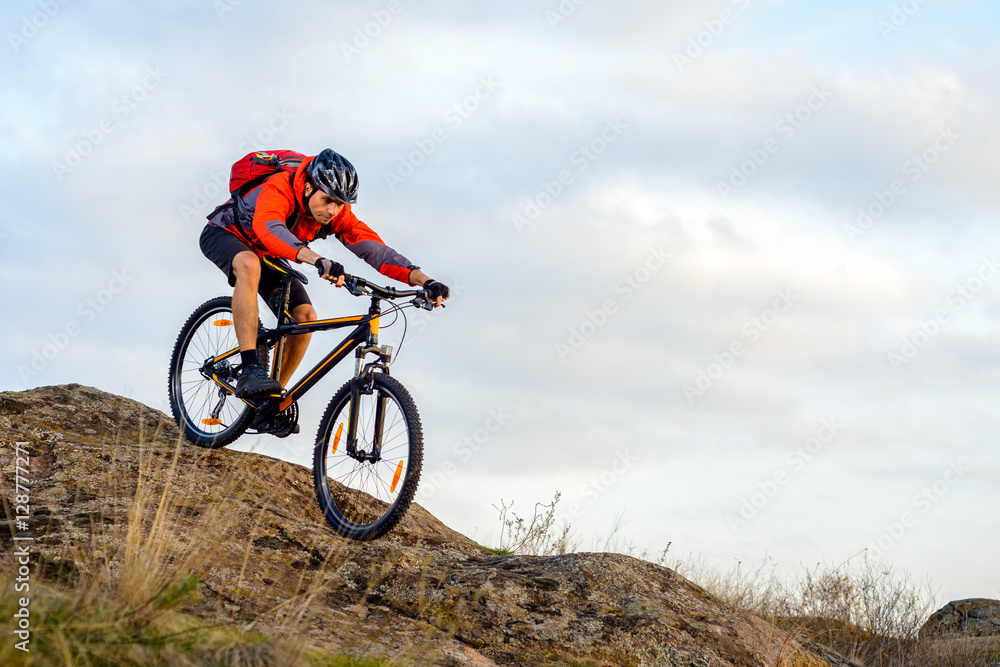 Cyclist in Red Jacket Riding the Bike Down Rocky Hill. Extreme Sport. Cyclist in Red Jacket Riding the Bike Down Rocky Hill. Extreme Sport.