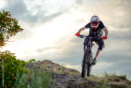 Fototapeta Naklejka Na Ścianę i Meble -  Professional Cyclist Riding the Bike Down Rocky Hill at Sunset. Extreme Sport.