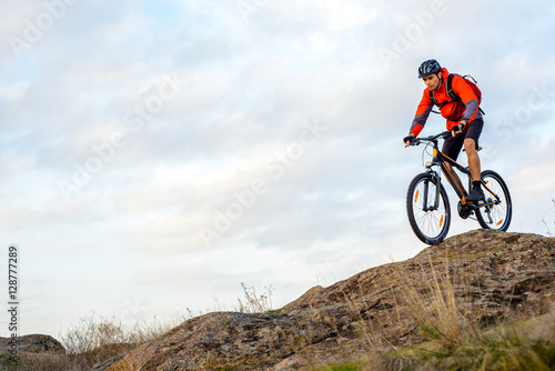 Fototapeta Naklejka Na Ścianę i Meble -  Cyclist in Red Jacket Riding the Bike Down Rocky Hill. Extreme Sport.