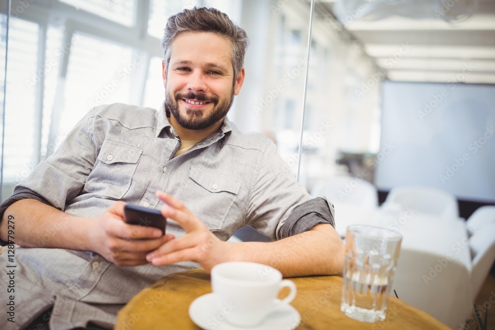 Smiling businessman using mobile phone in creative office Smiling businessman using mobile phone in creative office