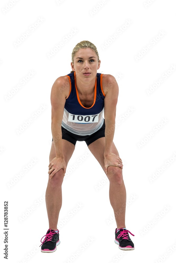 Tired athlete standing with hand on knee Tired athlete standing with hand on knee