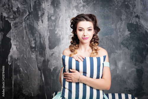 Attractive woman in retro blue dress with candles and striped pillow
