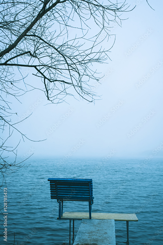 Lonely bench overlooking a winter lake or sea