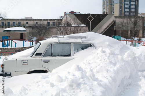The old car in the city covered with snow after a blizzard. Selective focus. © vladk213